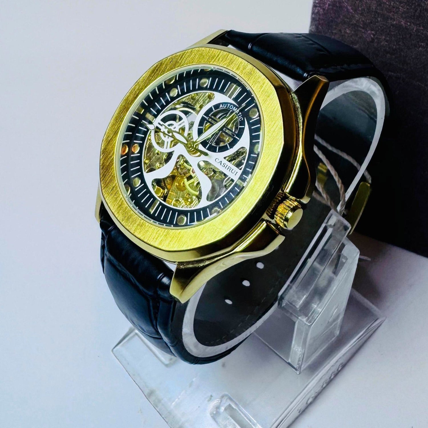 Elegant black and gold automatic skeleton watch with leather strap.